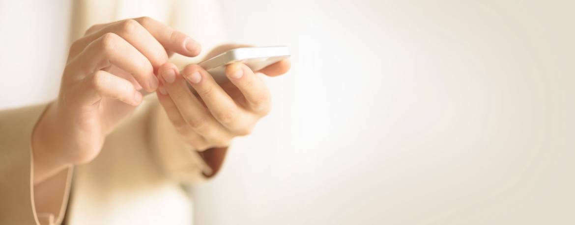 woman-hands-hold-cell-phone-on-light-cream-9H2WVTD-web.jpg